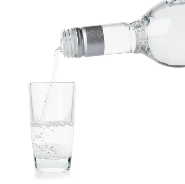 stock image Pouring of vodka from bottle into glass on white background