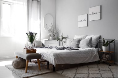 Çiçekler ve çiçek açan ağaç dallarıyla süslenmiş aydınlık yatak odasının içi.