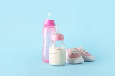Mavi arka planda poposu olan bebek için bir şişe süt.