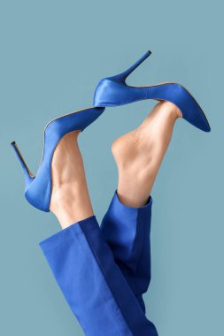 Mavi arka planda zarif yüksek topuklu genç kadın bacakları.