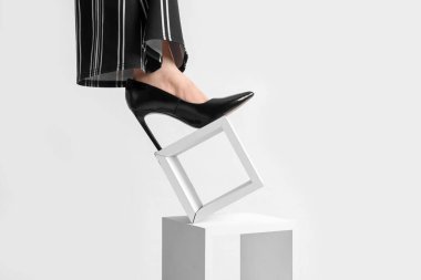 Siyah topuklu bir kadın, beyaz arka planda duruyor.