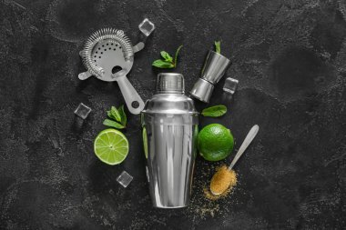 Titretici, süzgeç, ölçü kabı ve koyu arkaplanda mojito hazırlamak için malzemeler