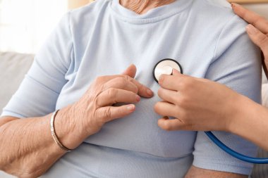 Kadın bakıcı, evde steteskoplu yaşlı bir kadın var, yakın plan.