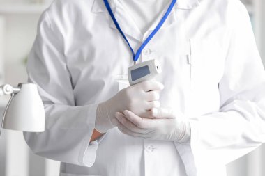 Klinikte kızılötesi termometresi olan olgun bir erkek doktor.