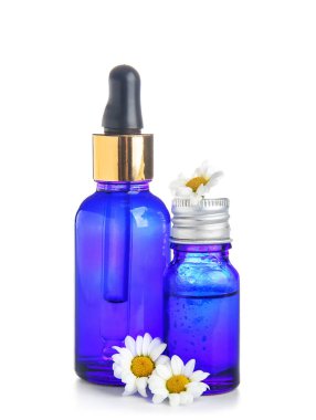 Beyaz arka planda sağlıklı yağ şişeleri ve papatya çiçekleri