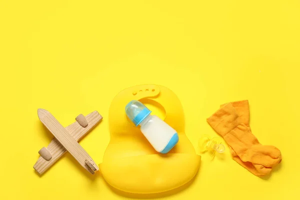 Bottle of milk for baby and  accessories on yellow background