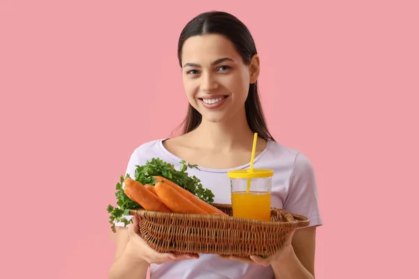 粉红背景的年轻女子 一杯蔬菜汁和胡萝卜 — 图库照片