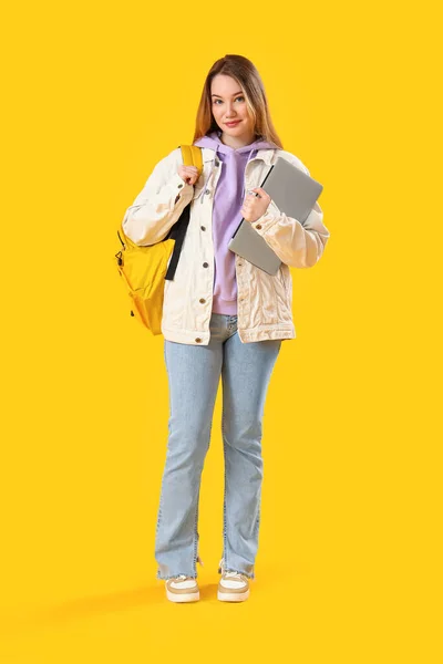 黄色の背景にラップトップを持つ女性学生 — ストック写真