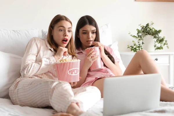 stock image Scared female friends with popcorn watching movie in bedroom