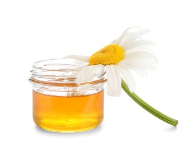 Beyaz arka planda cam kavanoz bal ve papatya çiçeği.
