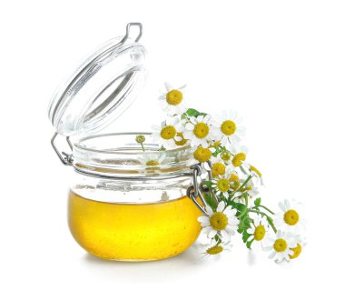 Cam kavanoz bal ve beyaz arka planda taze papatya çiçeği.