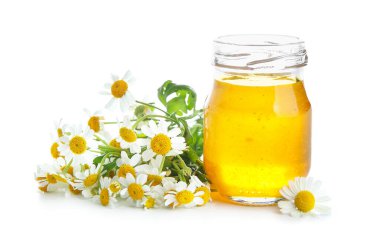 Cam kavanoz bal ve beyaz arka planda taze papatya çiçeği.