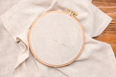 Kahverengi ahşap arka planda tuval ve iğneyle işlenmiş nakış halkası