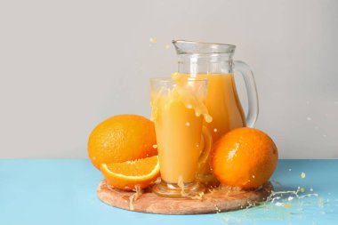 Bir sürahi taze portakal suyu ve gri arka planda su sıçraması.