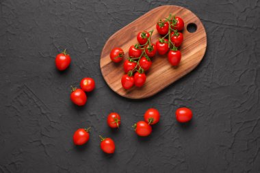 Siyah arka planda taze kiraz domatesli ahşap tahta.