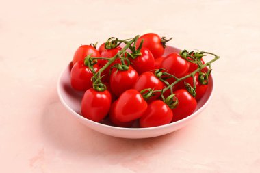 Pembe arka planda taze kiraz domatesli kase.