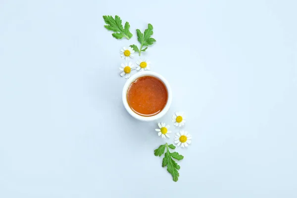 stock image Composition with bowl of honey, chamomile flowers and leaves on light background