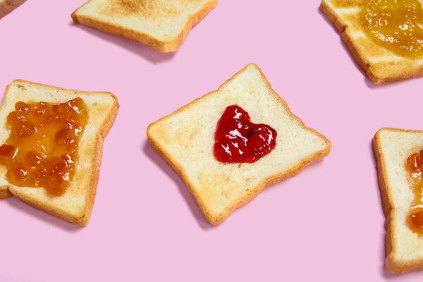 Toasts with different jams on pink background, closeup
