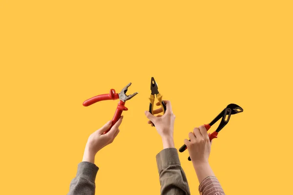 Female Hands Holding Different Pliers Yellow Background — Stock Photo, Image
