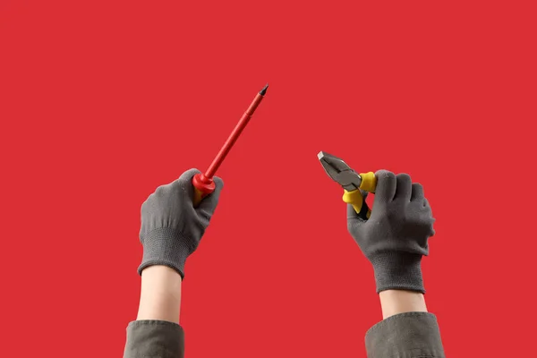 Vrouwelijke Handen Handschoenen Met Schroevendraaier Tang Rode Achtergrond — Stockfoto