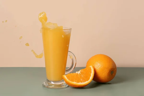 Szklanka Świeżego Soku Pomarańczowego Rozpryskami Stole Beżowym Tle — Zdjęcie stockowe