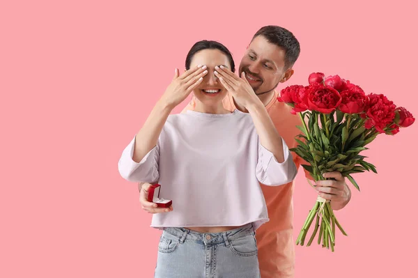 那个戴着订婚戒指 开着花的年轻人 把女朋友的眼睛闭在粉色背景上 — 图库照片
