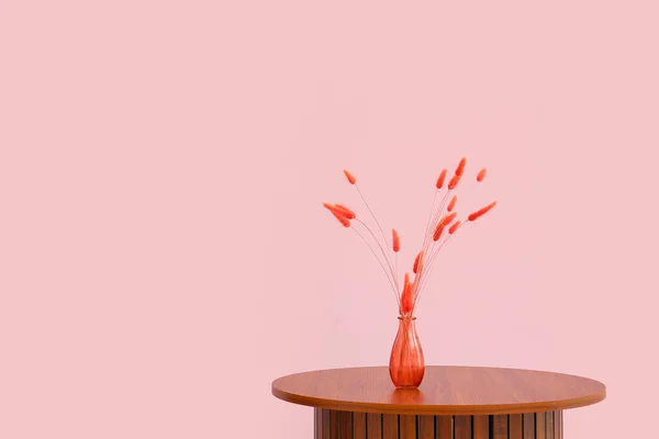 ピンク色の壁の近くの花瓶に赤いラグラスと木製のコーヒーテーブル — ストック写真