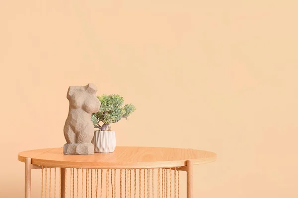 ベージュの壁の近くに盆栽と女性の人形と木製のコーヒーテーブル — ストック写真