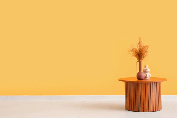オレンジの壁の近くの花瓶にパンパス草と木製のコーヒーテーブル — ストック写真