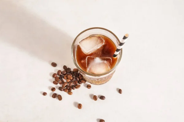 Ένα Ποτήρι Παγωμένο Καφέ Καλαμάκι Και Φασόλια Λευκό Φόντο Grunge — Φωτογραφία Αρχείου