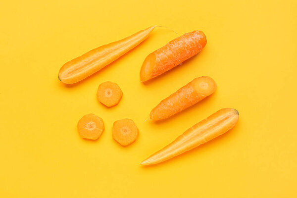 Fresh carrots and slices on orange background