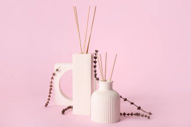 Pembe arka planda bir şişe çiçek kamışı ayırıcı.