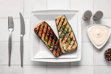 Lezzetli ızgara patlıcanlı tabak ve açık arkaplanda sos.