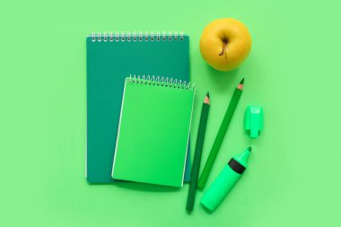Yeşil arka planda farklı kırtasiye malzemesi olan taze elma.