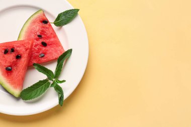 Taze karpuz parçaları ve sarı arkaplanda nane.