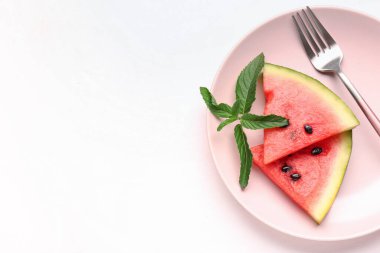 Beyaz zemin üzerinde taze karpuz ve nane parçalarıyla kaplı bir tabak.