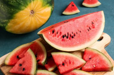Mavi arka planda taze karpuz parçaları olan tahta