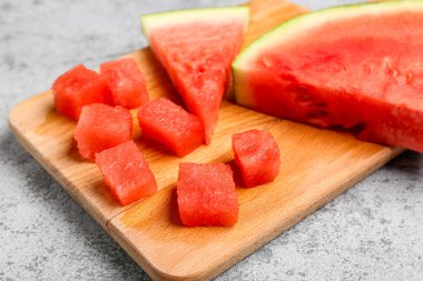 Gri arka planda taze karpuz parçaları olan tahta