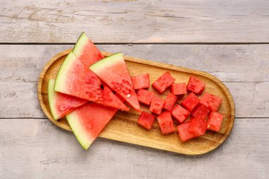 Gri ahşap arka planda taze karpuz parçaları olan tahta.