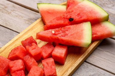 Gri ahşap arka planda taze karpuz parçaları olan tahta.