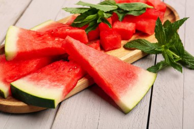 Taze karpuz parçaları ve gri ahşap arka planda nane.