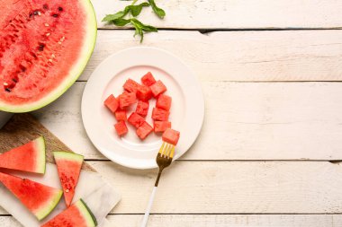 Beyaz ahşap arka planda taze karpuz parçaları olan tabaklar.