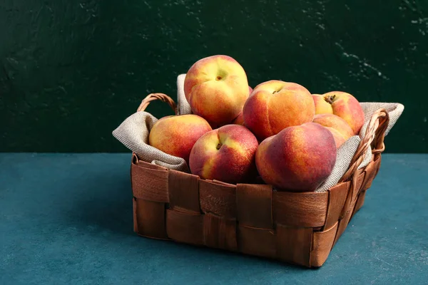 stock image Wicker basket with sweet peaches on blue table