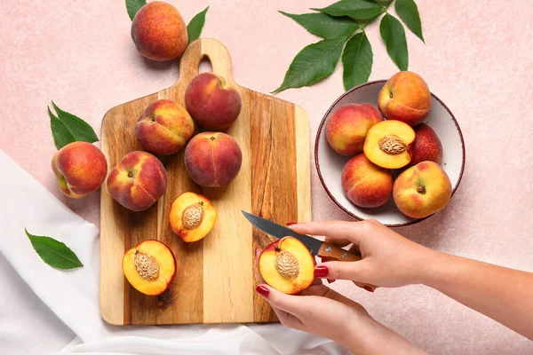 Frau Schneidet Süßen Pfirsich Auf Rosa Hintergrund — Stockfoto