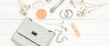 Beyaz ahşap arka planda şık kadın aksesuarları ve makyaj malzemeleri olan kompozisyon