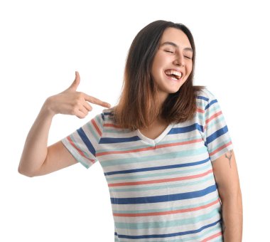 Mutlu genç kadın beyaz arka plandaki tişörtüne işaret ediyor.