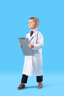 Mavi arka planda panosu olan sevimli küçük bir doktor.
