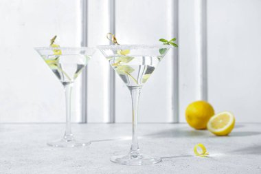 Beyaz masada bir bardak lezzetli martini ve limon.