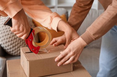 Genç çift taşınma gününde odada karton kutu kaydediyor. Kapatıyorlar.