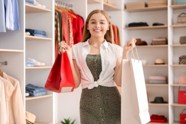 Butikte alışveriş çantalı genç bir kadın.